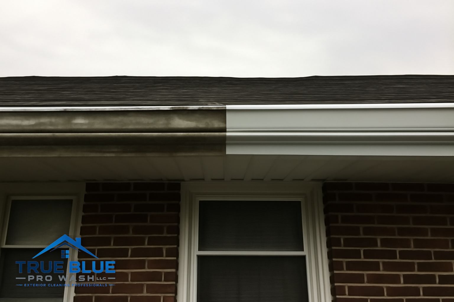 Technician removing packed leaf debris from aluminum gutters on a New Castle Delaware home